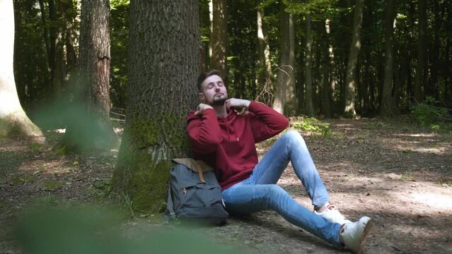 Unity with nature. Man sitting by tree in forest