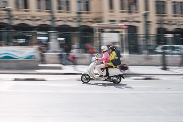 Two women driving a scooter in the city