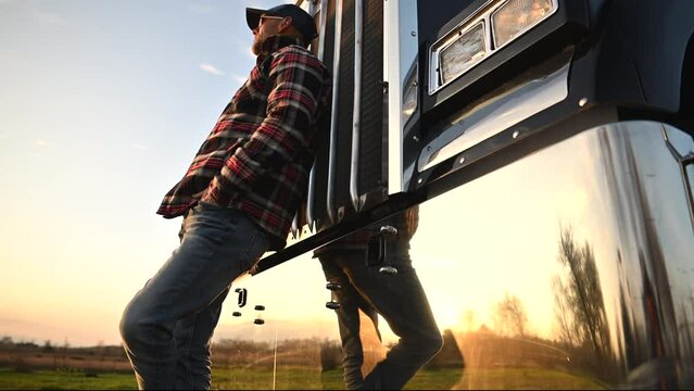 Caucasian Truck Driver Staying in Front of His Semi Truck Tractor During Sunset