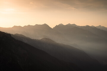 The sunset light shines behind the peaks of the Alps of Chiavenna Valley, Northern Italy