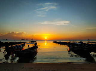 Wooden boat moored in shallow water near the beach at sunset. Romantic landscape.