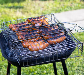 grilling sausages on a picnic outdoors on the green lawn