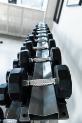 Fototapeta na wymiar Rack with dumbbells of different weights close up
