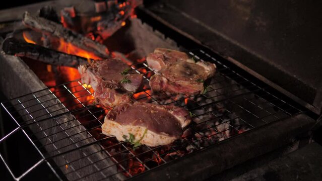 Close-up of a man's gloved hand laying out pieces of meat on bones at a barbecue. Cooking meat on the grill.
