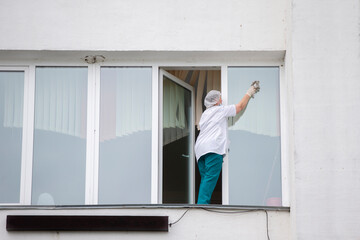 A nurse in a hospital or clinic washes windows. A cleaner in a medical facility.