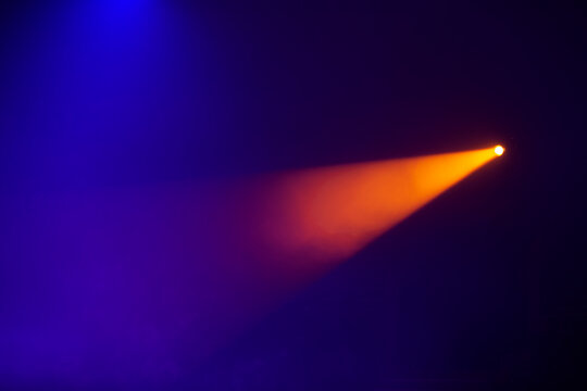 Orange beams of light from stage spotlights on a dark blue background.Illumination of the stage.