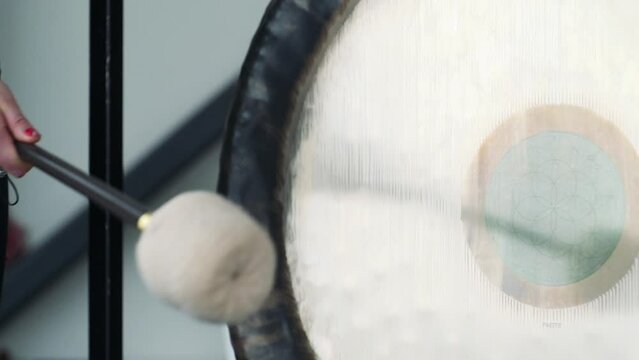 In this close up picture we can see women beating huge gong once.