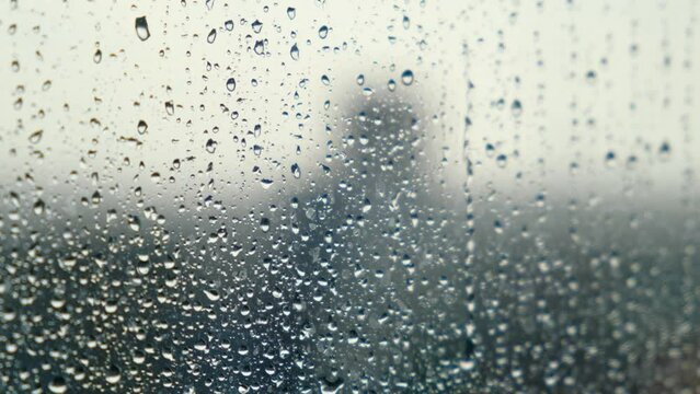 Raindrops flow down the window on a cloudy gloomy day