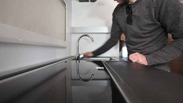 Caucasian Men Cleaning Motorhome Camper Van Kitchen Area with Soft Cloth and Cleaning Detergent. Hand Close Up. Keeping Recreational Vehicle Clean.