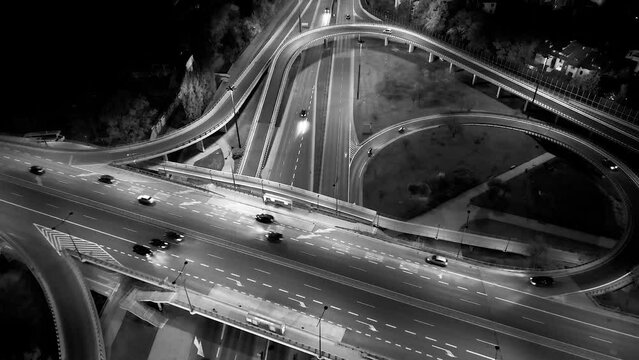 Drone shot of night traffic on a motorway showing cars and lanes of light with bridges and viaducts outside the city of Warsaw, Poland. Moving the camera forward.