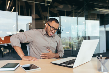 Businessman sick in office, man in glasses has severe stomach pain, african american man working...