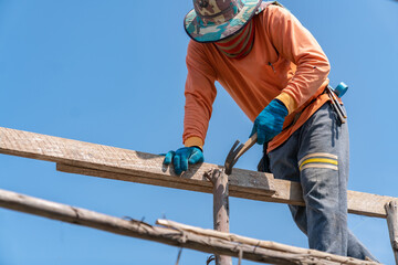 Worker use hammer hit nails on scaffolding for support second floor.