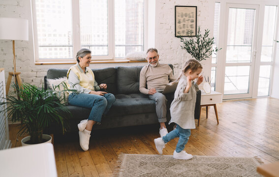 Cheerful Senior Grandparents Babysitting With Granddaughter