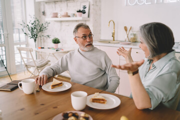 Cheerful senior couple enjoying breakfast together at home