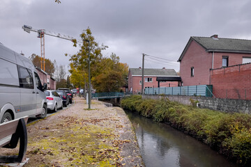Fototapeta na wymiar Cars parked on the roadside by Kleine Gete river in Zoutleeuw