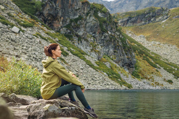 Naklejka na ściany i meble Woman solo traveler looks at the beautiful view of mountain lake