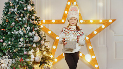 Little girl with a Christmas present in a room decorated for Christmas. Christmas background with...