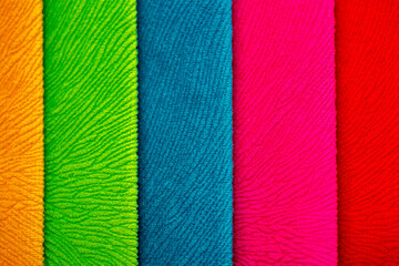 Fabric swatches in different colors are stacked for selection. A variety of shades of upholstery material for furniture and interior. Fabric texture close up. A set of multi-colored rolls of material.
