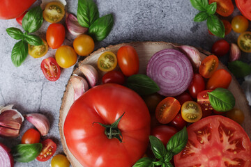 Flat lay composition of different tomatoes, onion, basil and garlic	
