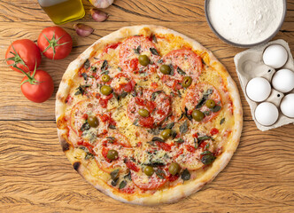 Cheese pizza with tomatoes, olive oil, eggs and flour over wooden table