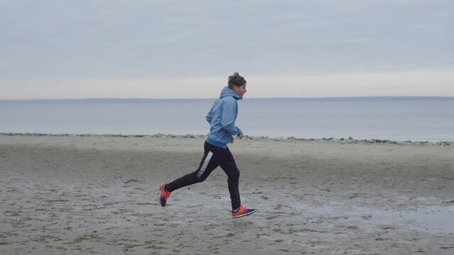 Slow-motion video of a man running through mud and puddles on a morning run. An athlete prepares for a marathon and runs in difficult conditions in nature. High quality 4k footage