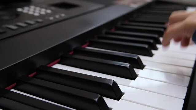 Children's fingers play on the keys of a piano synthesizer. Selective focus on piano keys