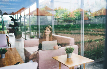 Thoughtful woman with netbook in cafe