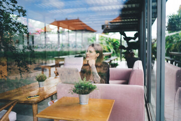 Thoughtful female freelancer with netbook in cafe