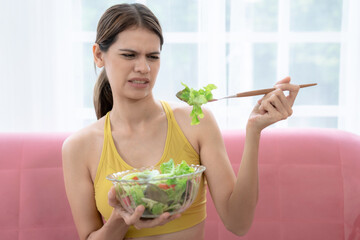 Unhappy young Caucasian woman does not want to eat vegetables and does not like the bitter taste of...
