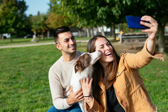 Happy couple with dog taking picture in park