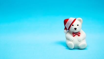 toy white bear in a christmas hat and a bow tie on a blue background