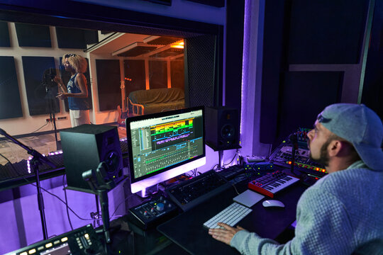 Professional sound engineer recording singer in studio