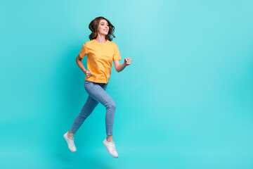 Full length photo of dreamy shiny lady wear yellow t-shirt jumping high running empty space isolated turquoise color background