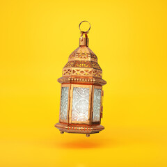 Golden glowing Arab lantern floating on a yellow background, 3d render