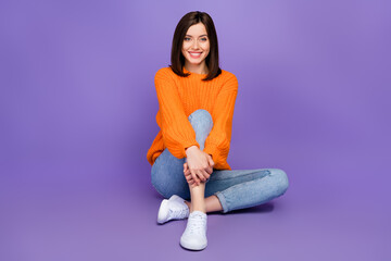 Full body photo of pretty young woman sitting floor hug knee smiling wear trendy knitwear orange outfit isolated on violet color background