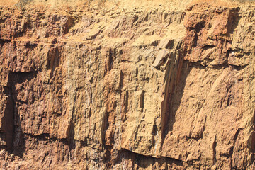 The rocky edge of the ground failed. Orange-red rock on the dip in the ground.