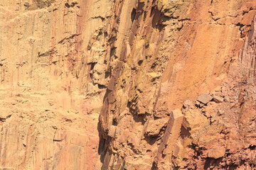 The rocky edge of the ground failed. Orange-red rock on the dip in the ground.