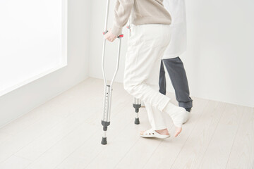 骨折して松葉杖を使って歩く女性　顔無し