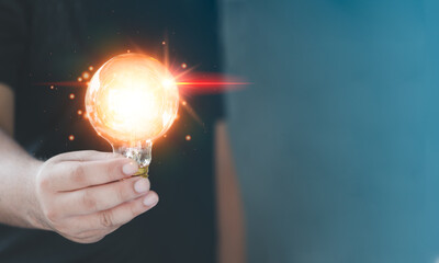 Idea innovation and inspiration concept. Hand of man holding illuminated light bulb, concept creativity with bulbs that shine glitter. Inspiration of ideas for sustainable business development.