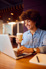 Young Businesswoman In Modern Open Plan Office Working On Laptop In Seating Pod With Coffee