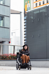 Brunette woman sitting in wheelchair on city street