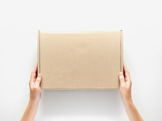 female hands holding a cardboard box on a white background. packaging and delivery concept, top view