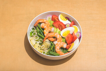 Rich seafood salad bowl with vegetables on the orange warm  Earth tones background. Large shrimp, potatoes, avocados, eggs, tomatoes, green beans. Healthy dinner, lunch. Natural cuisine concept