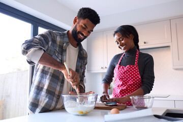 Couple At Home Baking Cake Together In Kitchen