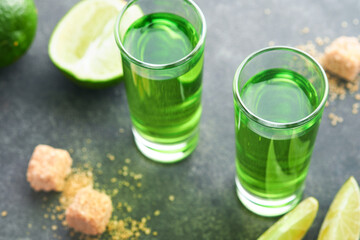 Absinthe. Two glasses of absinthe with cane sugar and lime on dark background. Strong alcoholic drink. Bar card concept. Place for text.