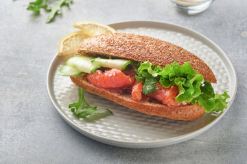 Sandwiches with salted salmon. Open sandwiches from cereal or whole grain rye bread with salted salmon, sesame seeds and dried tomato on white marble stand. Seafood. Healthy food. Scandinavian cuisine