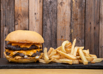 American food. Closeup view of a monster burger with meat, cheddar cheese and onion with french...