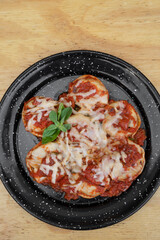 Stuffed pasta. Top view of sorrentinos with a mediterranean tomato sauce and provolone cheese in a black dish on the wooden table. 