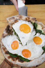 Eating pizza. Closeup view of a woman's serving a slice of pizza with mozzarella cheese, spinach and a fried egg.