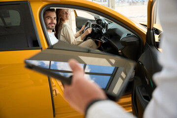 Naklejka premium Young couple choosing motor vehicle at dealership